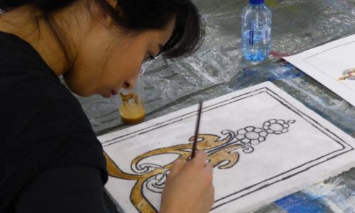 Een leerling werkt aan een sgraffito