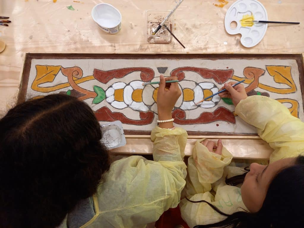 Twee leerlingen schilderen een sgraffito.
