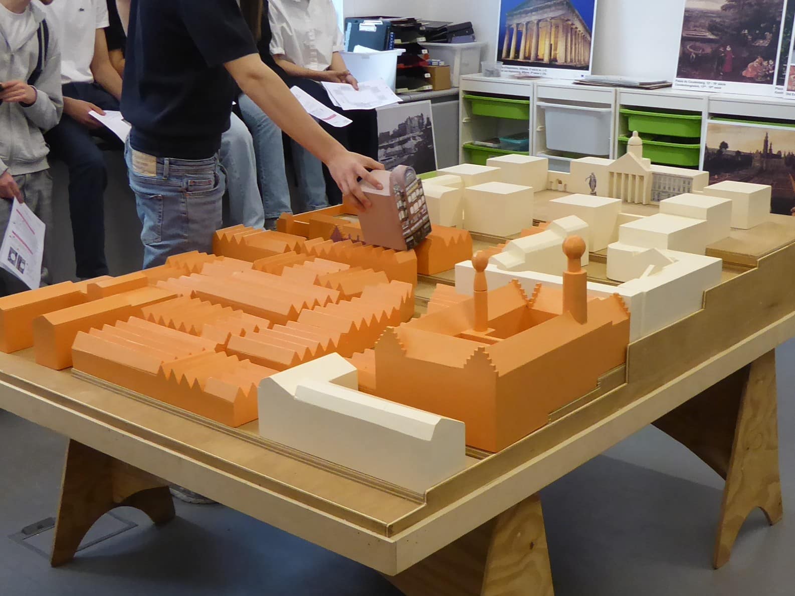 Een leerling zet in een lokaal een maquette van de Koningswijk in elkaar.