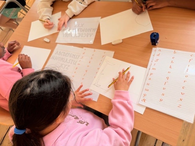 Leerlingen maken een kalligrafie van hun eigen naam.